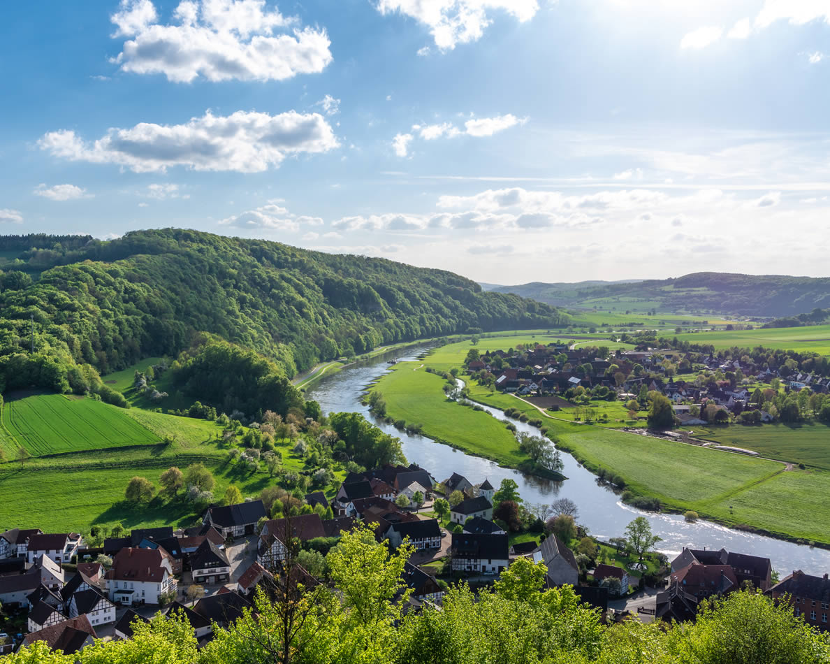 Landschaft mit einem Fluss in der Mitte und Häusern